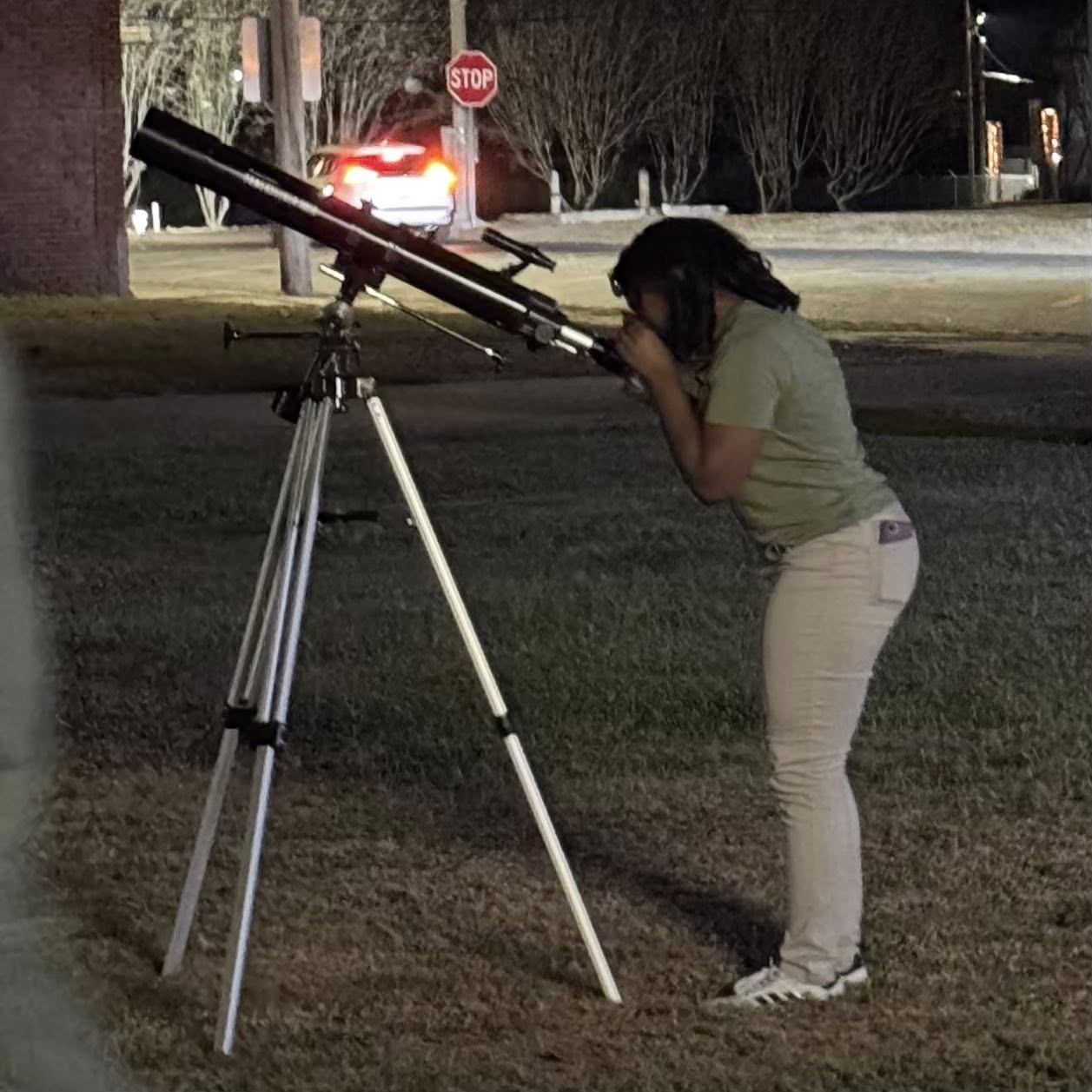 A girl looking through a telescope.